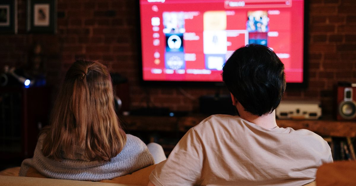 Two people sitting close together on a sofa, each holding a game controller